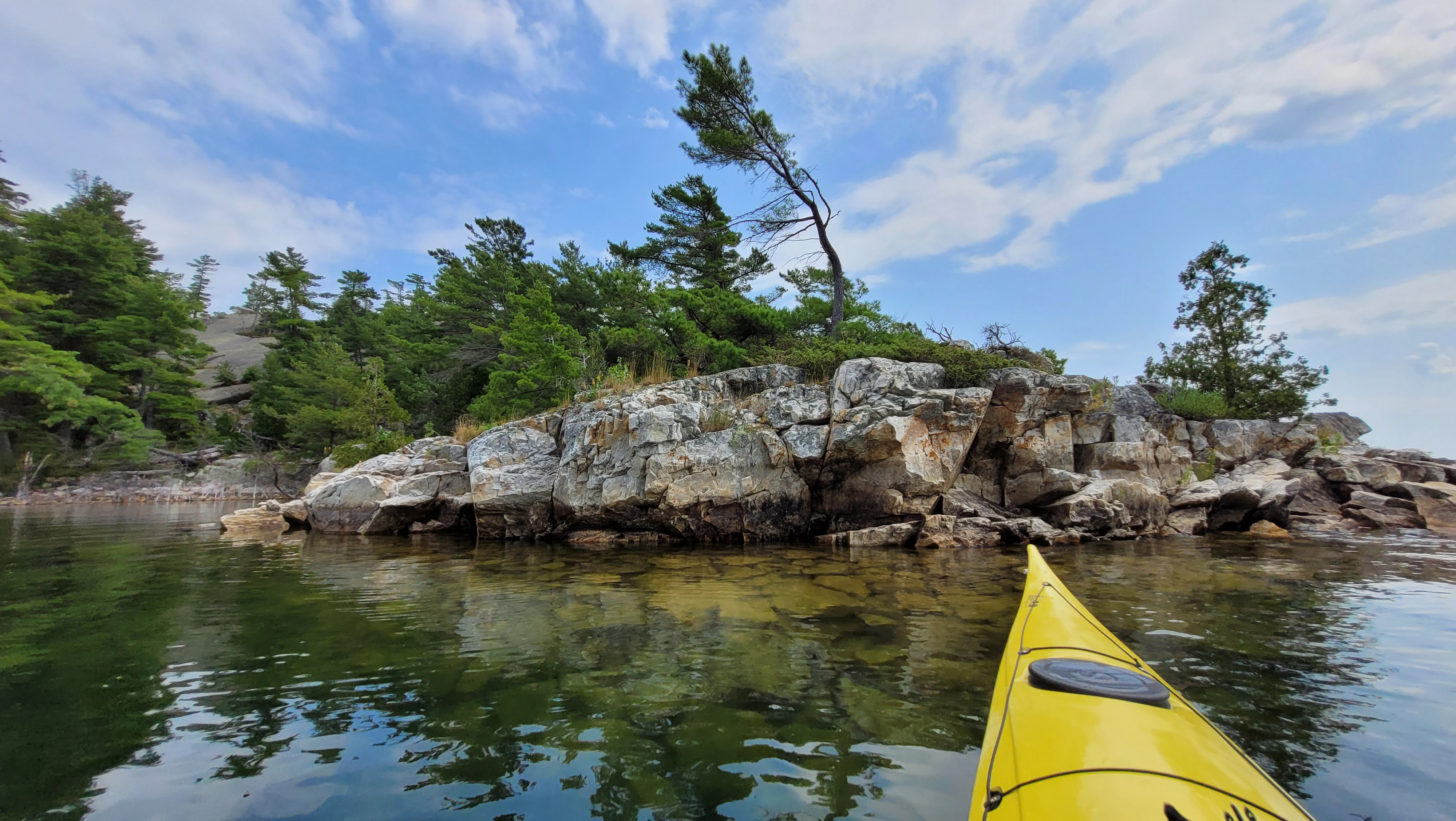 Western Shoreline of the Benjamind islands with red granite rock, white quartzite,
                trees and clear water